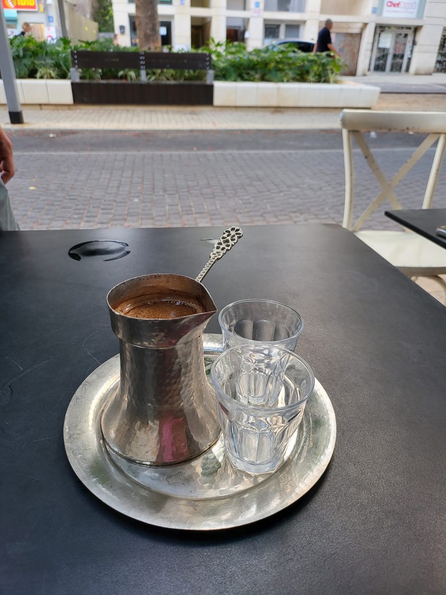 קפה בכלי מתכת לצד כוס מים